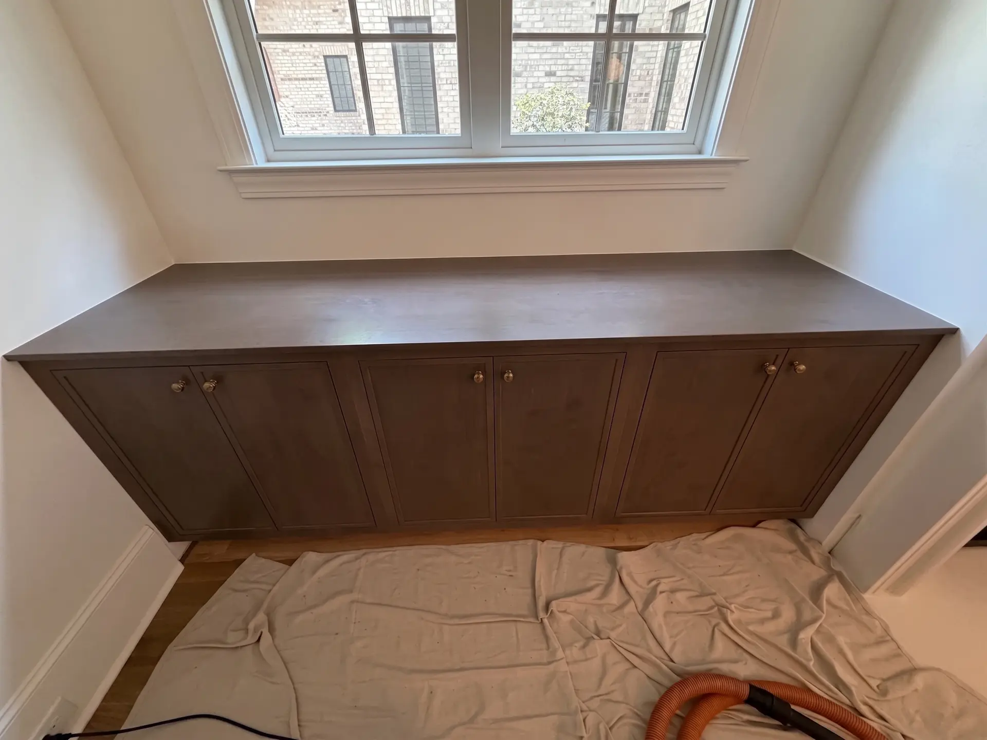 Custom cabinet installation under a window by Complete Handy Solutions