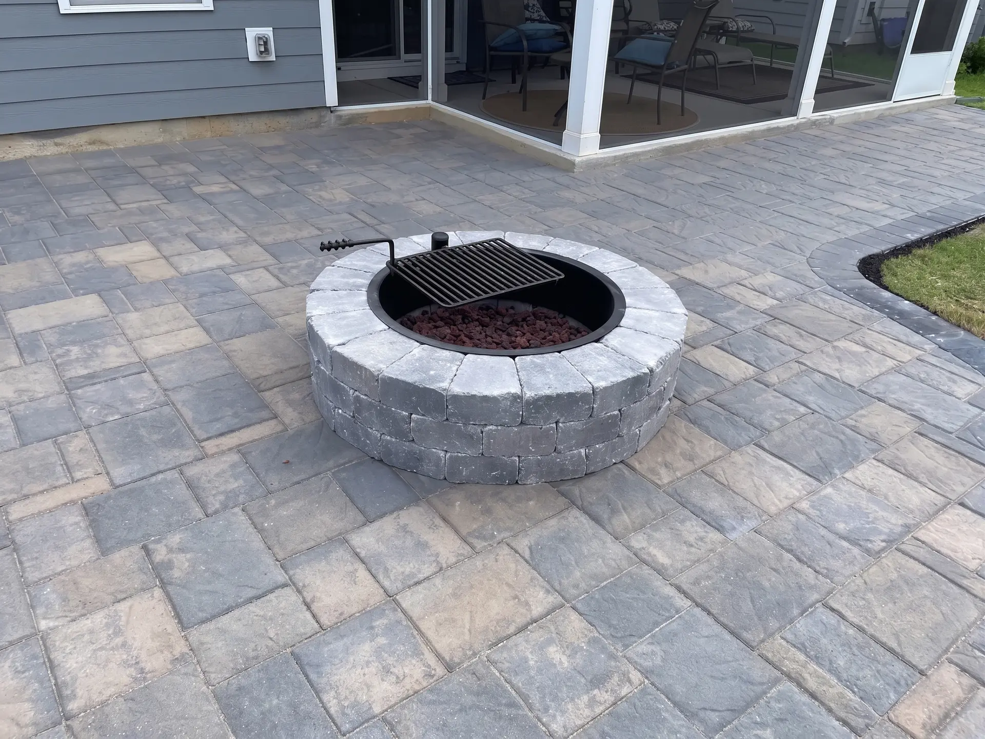 Paver patio with fire pit and grill by Complete Handy Solutions